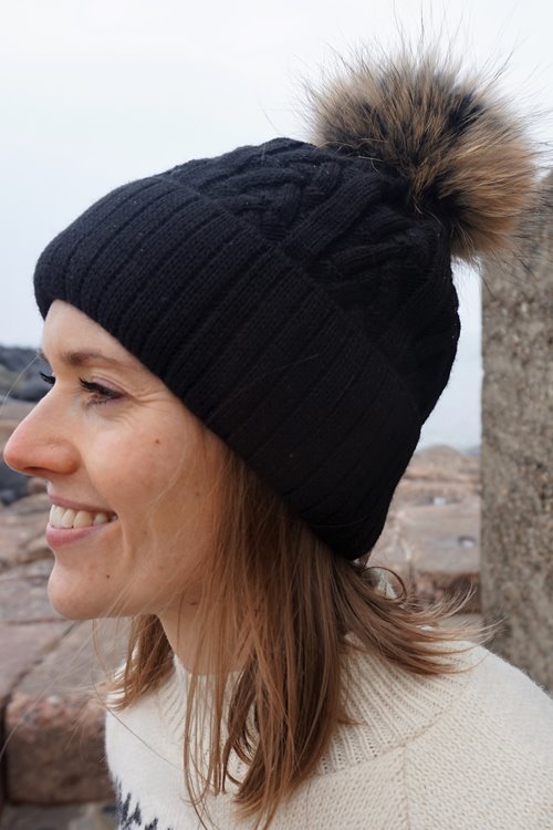 Knitted hat MARIKA in black with a pompom made of Finnish raccoon fur.